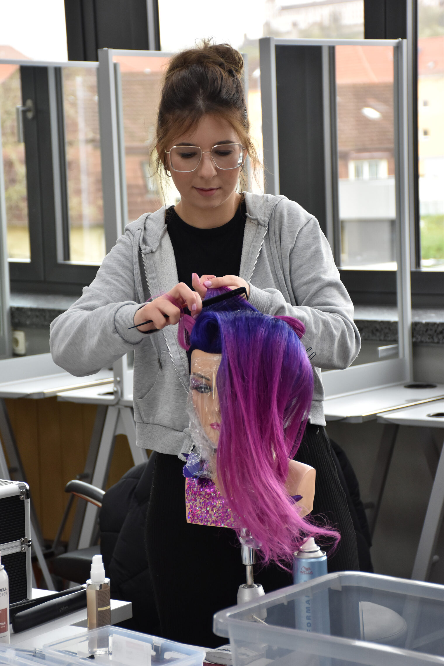 Eine Meisterschülerin kämmt einer Übungspuppe die Haare.