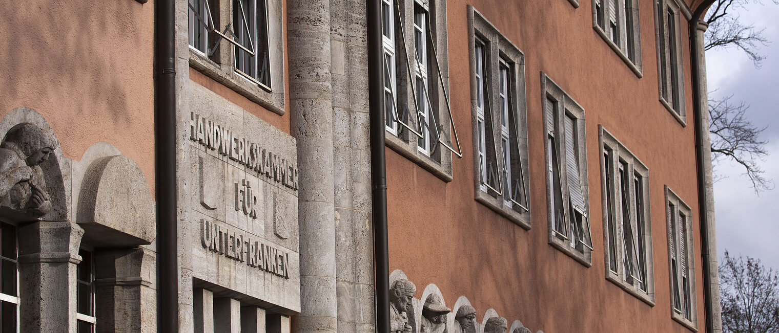 Fassade der Handwerkskammer-Hauptverwaltung mit in Stein gemeißelter Schrift "Handwerkskammer für Unterfranken" und Wappen