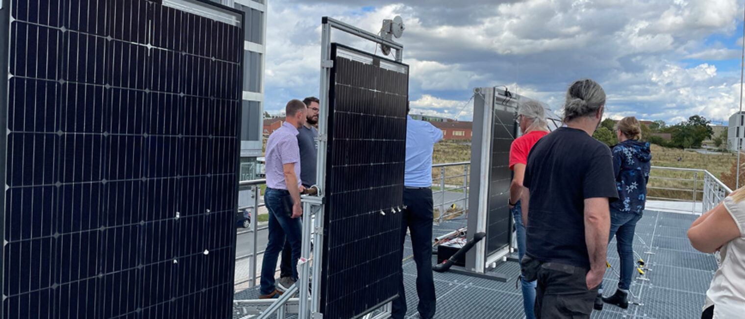 Gruppe schaut sich PV-Panele auf einem Dach an