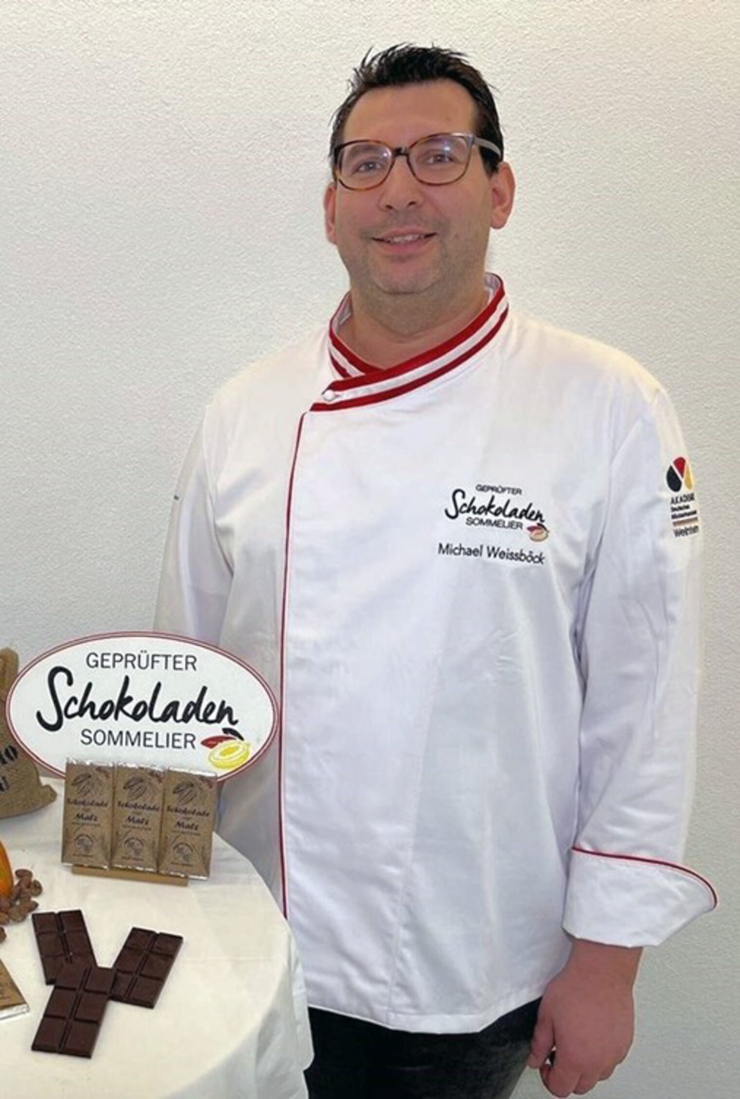 Der Dozent Michael Weissböck trägt die Jacke für geprüfte Schokoladen-Sommelière und lächelt in die Kamera.