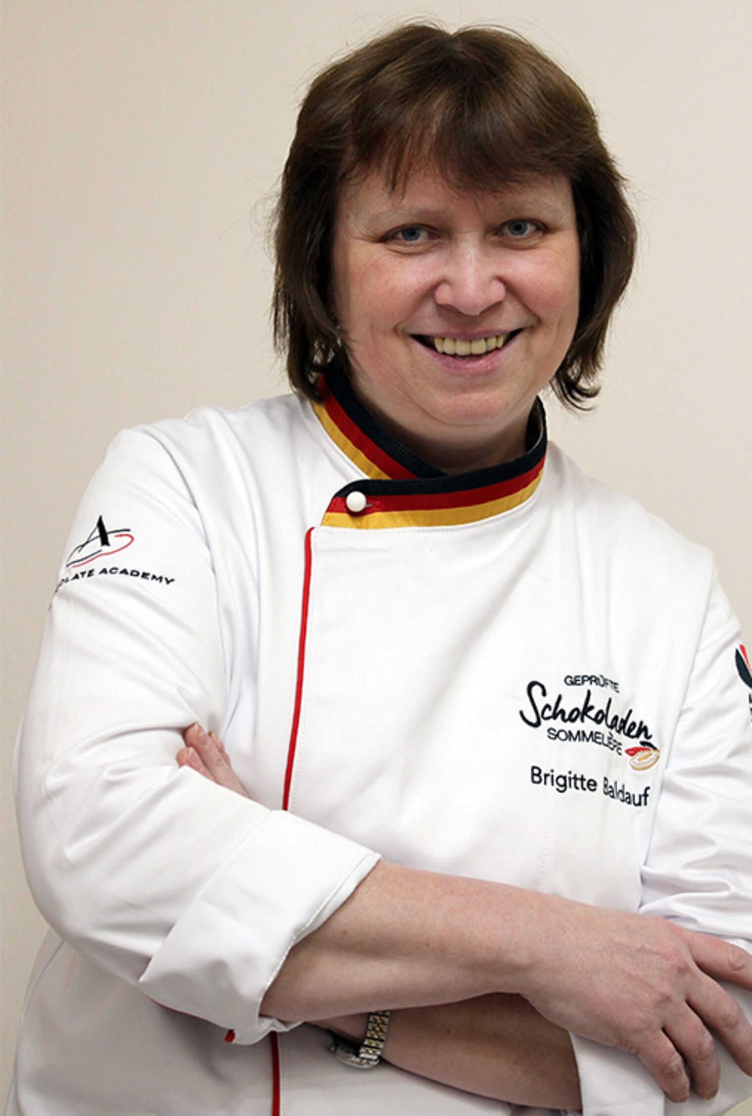 Die Kursleiterin Brigitte Baldauf trägt die Jacke für geprüfte Schokoladen-Sommelière und lächelt stolz in die Kamera.