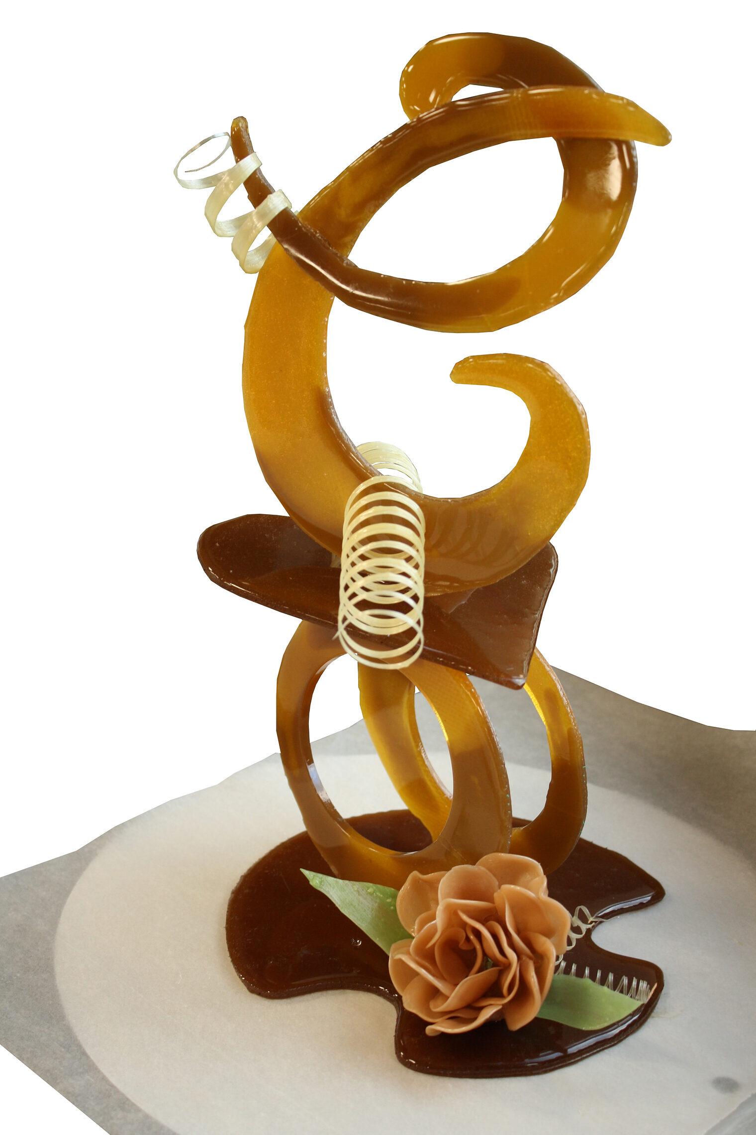 Eine kunstvolle Zuckerskulptur bestehend aus ineinandergreifenden Spiralen aus bernsteinfarbenem Zucker und einer Zuckerrose.