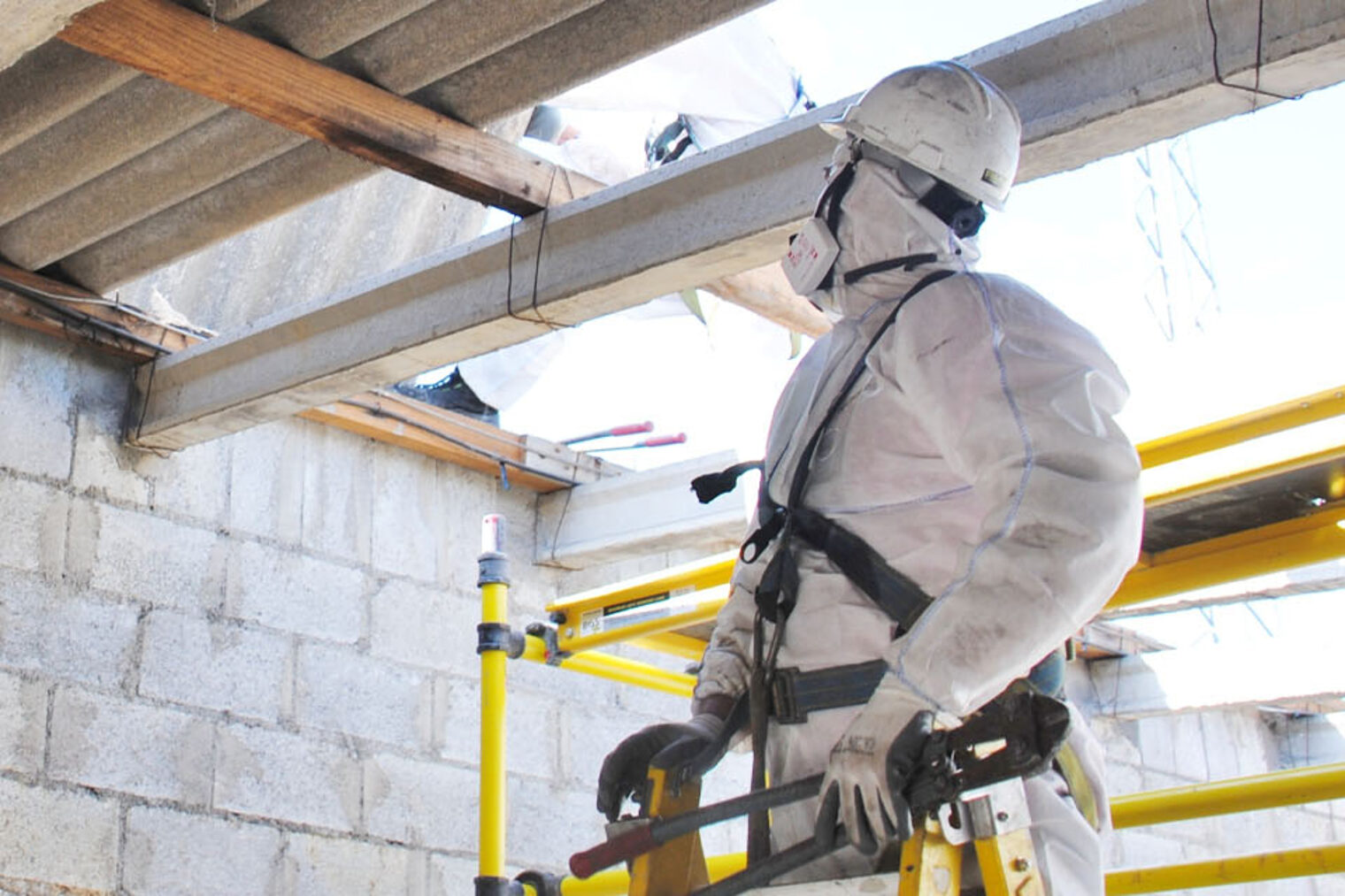 Bauarbeiter in Schutzanzug auf Baustelle vor Asbestplatten