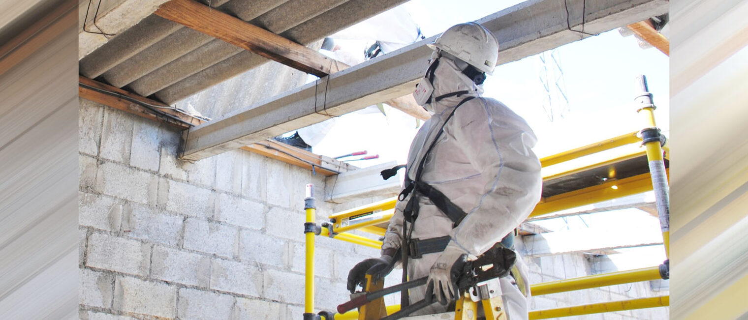 Asbest / Gefahrstoffverordnung Bauarbeiter in Schutzanzug auf Baustelle vor Asbestplatten
