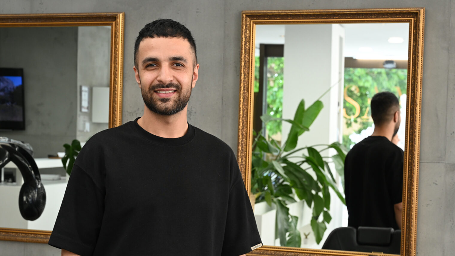 Friseurmeister in einem Salon schaut in Kamera