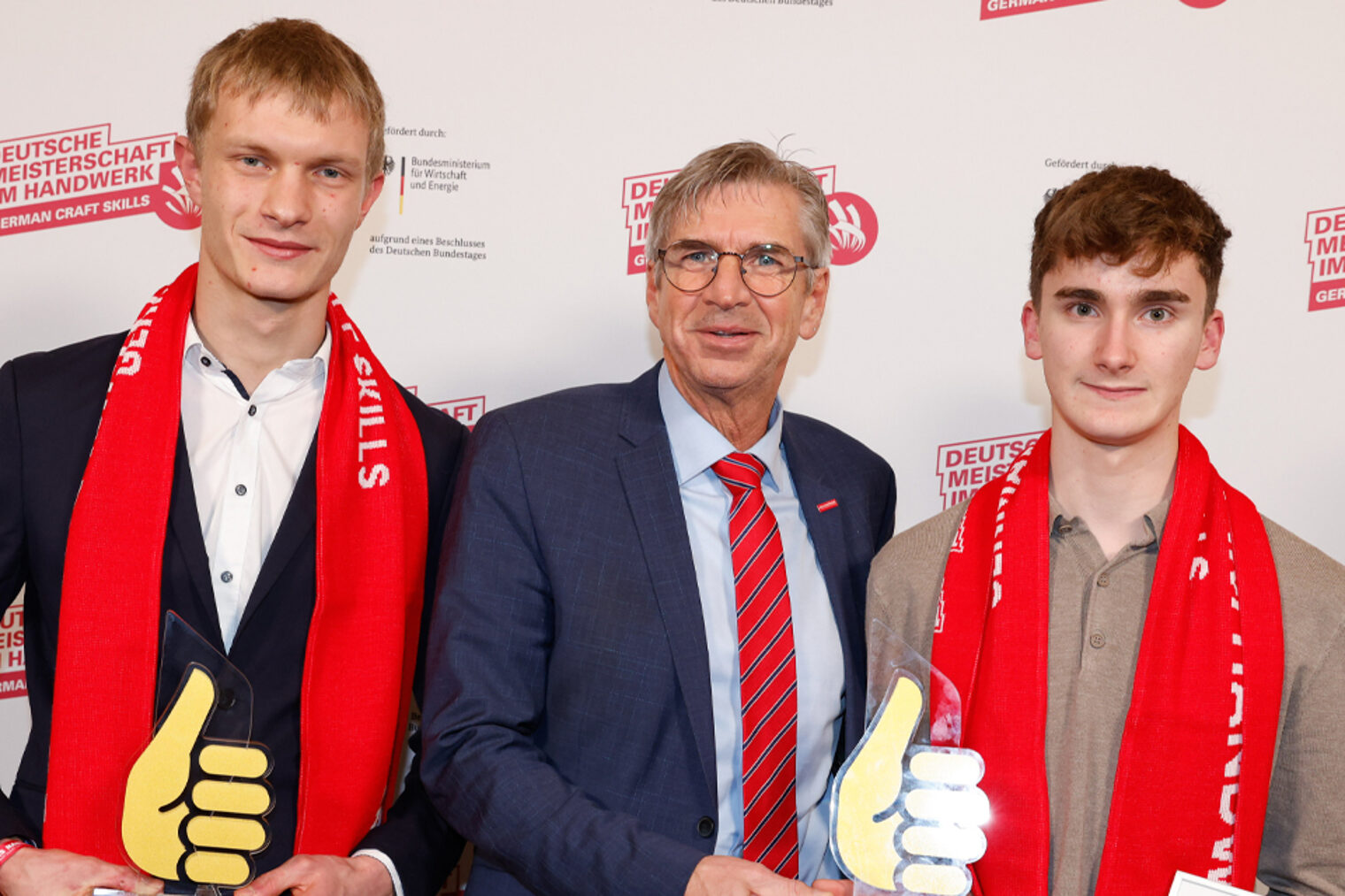 Gruppenfoto drei Personen vor Fotowand