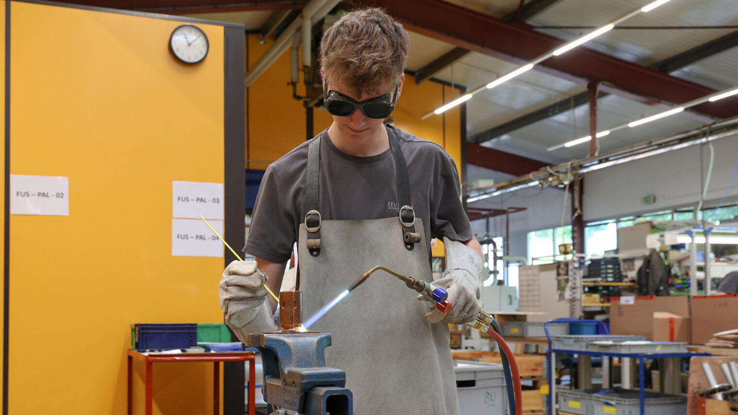 Junger Feinwerkmechaniker lötet ein Bauteil