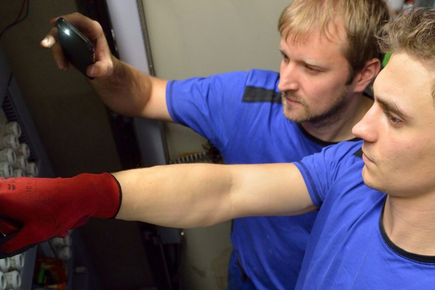 Ein junger Mann mit blauem Oberteil zeigt mit dem Finger auf diverse Schalter